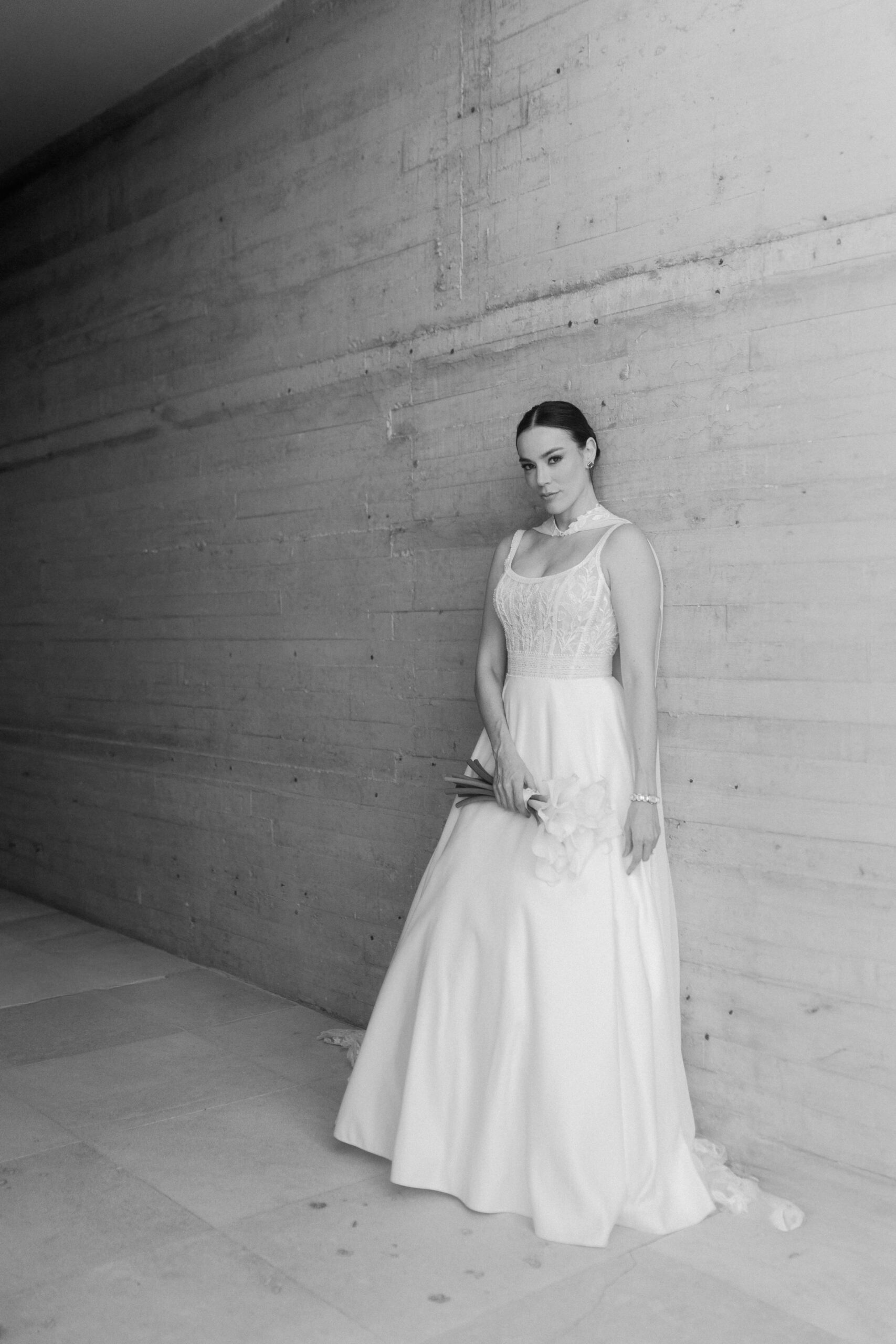 una novia muy elegante posando en su boda con un fondo gris a blanco y negro